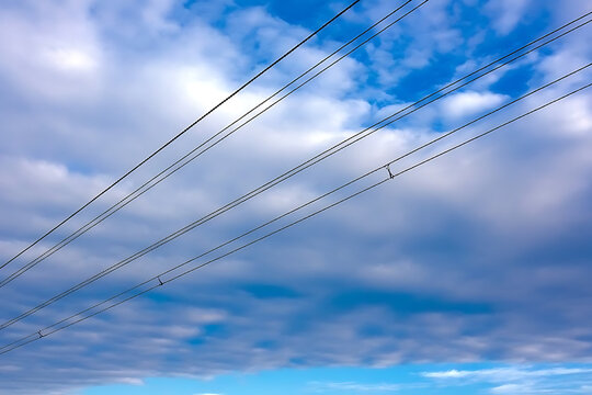 View of power lines against a cloudy blue sky with puffy white clouds overhead view - Powered by Adobe