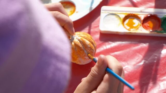 Image 7: Decorate with paints a small pumpkin. A teen hands make a decoration for party and painting a pumpkin