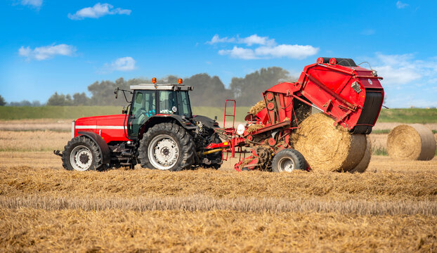 Tractor with round baler on the harvested grain field - 0167