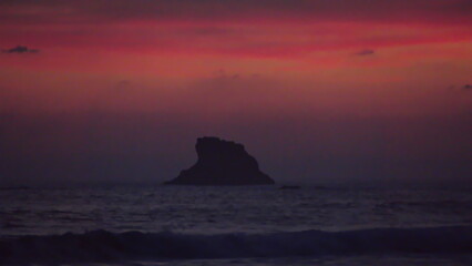 Silhouette of a rocky islet off the beach in Zipolite, Mexico, at sunset