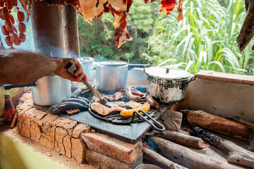 Man Grilling Traditional Colombian Meat on Rustic Wood-Fired Stove