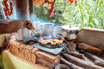 Man Cooking Meats Over Wood-Fired Stove in Traditional Colombian Outdoor Kitchen