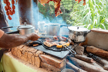 Close-Up of Hand Grilling Meats on Traditional Wood-Fired Stove in Colombia