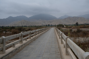Bridge over the Supe River in the Lima Region, Peru, with the characteristic arid mountains of the area in the background.
