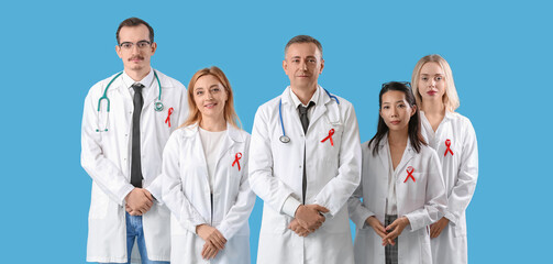 Professional team of doctors with red ribbons on blue background. World AIDS Day concept