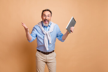 Confident mature male entrepreneur showcases modern technology in a stylish and casual setting on beige background