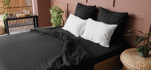 Interior of stylish bedroom with black linen and plants