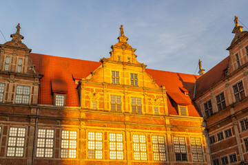 Gdansk, a city on the Baltic coast of northern Poland, Europe. Picturesque architecture with red roofs and golden sunlight on building facades. A captivating urban scene blending history and warmth.