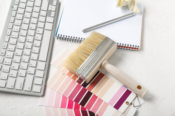 Color palettes, PC keyboard, notebook and brush on light background