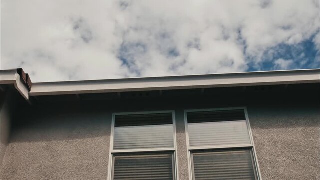 Time lapse of Two windows and a rooftop on a modern stucco home