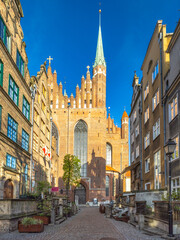 Fototapeta premium Gdansk, a city on the Baltic coast of northern Poland, Europe. Majestic cathedral towering over a charming cobblestone street, its spire reaching into the clear blue sky in an old European city.