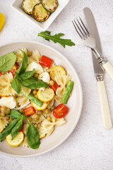 Plate of tasty pasta salad with peas and basil on white background