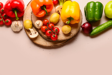 Wooden boards with different fresh vegetables on beige background
