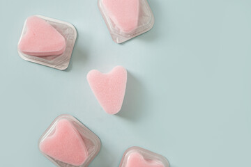 Set of female pink tampons stringless as heart in individual package on blue background. New generation. Hygiene accessories for women. View from above.