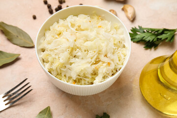 Bowl with delicious sauerkraut and different spices on pink background