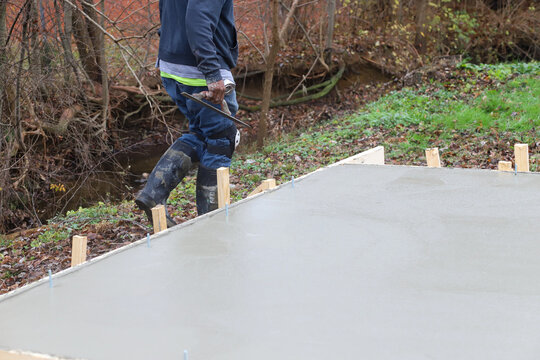 Crew of concrete workers pouring and leveling a shed pad