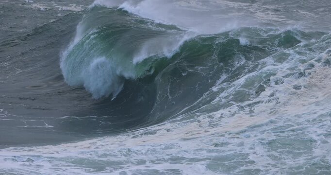 A huge ocean wave curls and breaks on a shallow bombora reef, exploding into a wall of white water during a coastal storm swell. Captured in slow motion during an east coast low.