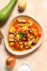 Bowl with delicious beef stew and different ingredients on beige background