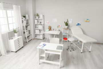 Blurred view of pediatrician's office with table, couch and children's drawings