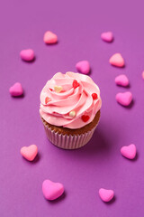 Tasty cupcake with hearts for Valentine's Day on purple background
