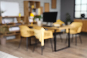 Blurred view of stylish office with workplace and shelf units