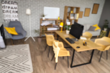 Blurred view of stylish office with workplace, shelf units and plants