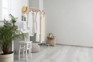 Small refrigerator with cosmetic products and houseplant on table in light room