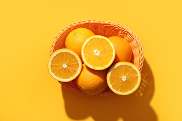 Beautiful composition with ripe oranges in wicker basket on orange background