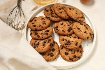 Plate of sweet cookies with chocolate chips on white background