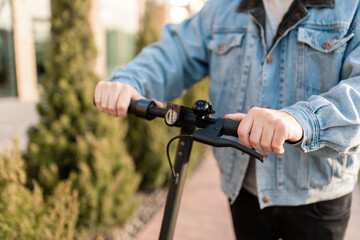 Close-up of male hands holding the steering wheel of an electric scooter. © zadorozhna