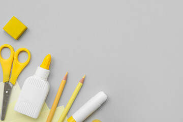 Bottle of glue, stick glue, scissors and pencils on grey background. Top view