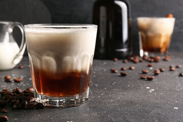 Glass of White Russian cocktail and coffee beans on black background