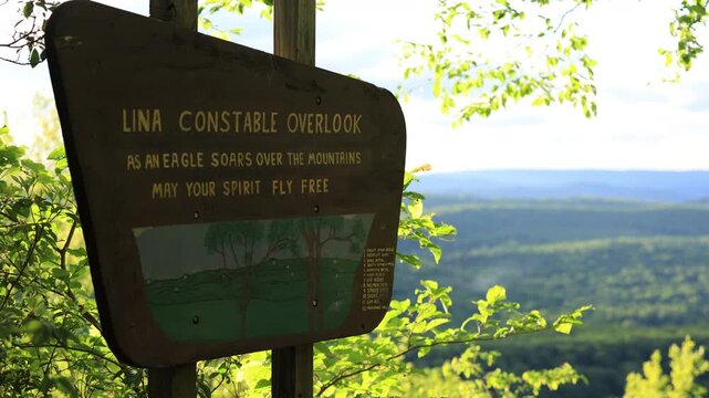 Lina Constable Overlook in summer. A wooden sign honors the view as forested ridges stretch into the distance under soft afternoon light. Peaceful, scenic, and full of natural beauty. Lost City, WV.