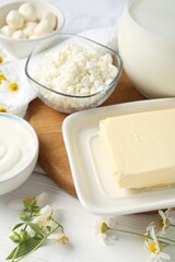 Fresh dairy products and flowers on white wooden table, closeup