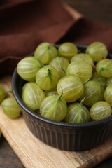 Fresh green gooseberries in bowl on table, closeup