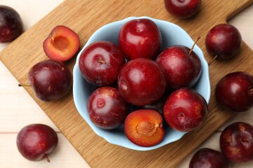 Ripe cherry plums on light wooden table, flat lay