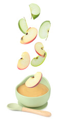 Baby food. Apple slices falling into bowl of puree on white background