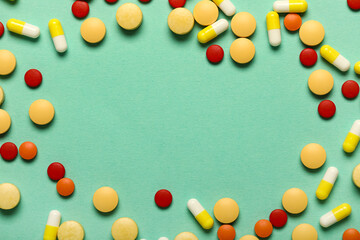 Frame made of different pills on green background