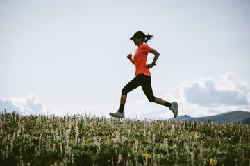 Trail runner running on the high altitude grassland mountain trail