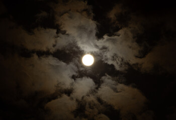 Dark sky with full moon partially hidden by clouds. Blue and black tones enhance the eerie lunar mood&mdash;ideal for Halloween, night nature, or planet photography.