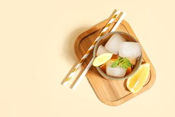Glass of Long Island iced tea cocktail with mint on beige background