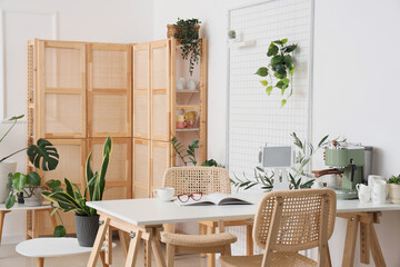Interior of light kitchen with houseplants, modern coffee machine and tablet computer on table