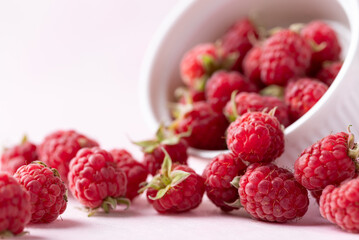 Fresh ripe raspberry with leaf in bowl on pink background, Summer fruit