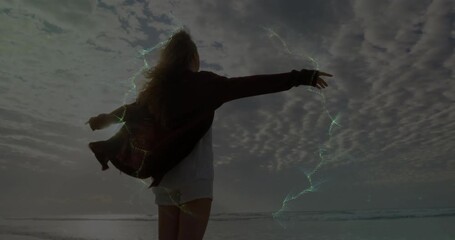 Woman standing beach breeze sparking energy spiraling around arms demonstrating technology - Powered by Adobe