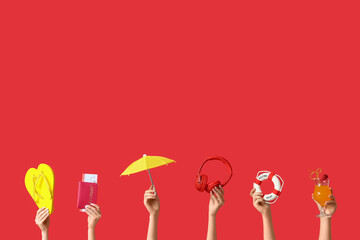 Female hands with beach accessories on red background. Tourism concept