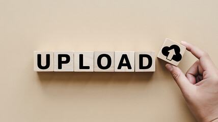 Hand placing a wooden block with an upload icon onto the word upload spelled out with wooden blocks