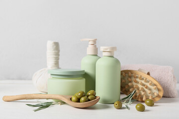Set of natural cosmetic products, spa accessories and green olives on light wooden table