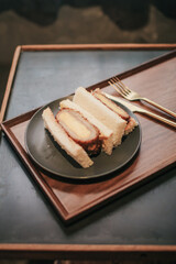 Sandwich with japanese omelet and pork. Tamako in bread on wooden tray. Morning breakfast.