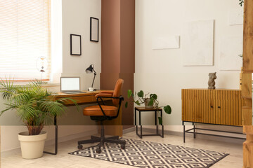 Interior of modern home office with stylish workspace, laptop and houseplant