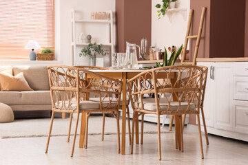 Interior of stylish open space kitchen with sofa, dining table and houseplants